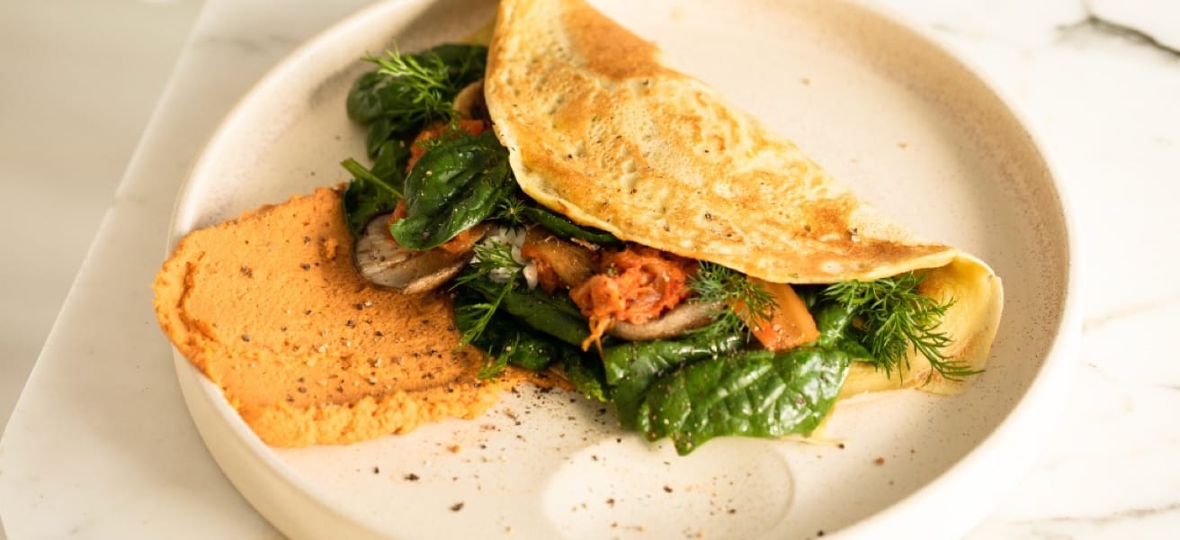 A delicious omelette filled with fresh spinach, mushrooms, and herbs, served on a white plate.